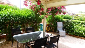 An outdoor patio with a table and chairs, surrounded by lush greenery and flowering plants. - Air-Conditioned Cottage with Large Terrace, Near Beach and Shops (Argelès-sur-Mer)