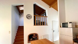 A kitchen with a microwave, a dining table, a staircase, and a fireplace. - Cozy Renovated Home with Large Garden, Pergola, and WiFi - Near Beach, Sleeps 5 (Bretignolles-sur-Mer)
