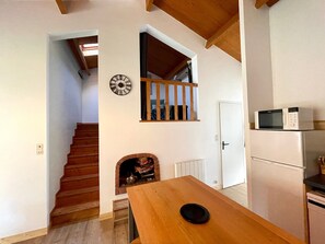 Une cuisine équipée d’un four à micro-ondes, d’une table à manger, d’un escalier et d’une cheminée.