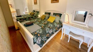 A bedroom with a bed, a dresser, a mirror, and a chandelier.