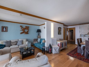 A spacious living room with a sofa, a coffee table, and a dining area with a table and chairs. - Spacious Val Thorens Apartment 3 Bedrooms with Sauna and Ski-in/Ski-out Access (Val Thorens)