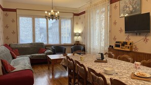 Una sala de estar acogedora con un sofá, sillas, una mesa de comedor y un televisor.