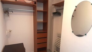 A room with a wooden wardrobe, a mirror, and a small table. - Air-conditioned studio with balcony and parking, Cap d'Agde (Cap d'Agde naturisme)