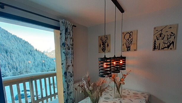 Ein Zimmer mit Balkon, einem Tisch mit gemustertem Tischläufer und Wandbildern.