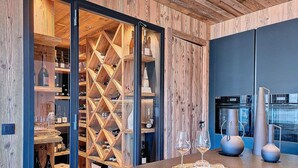 Cozinha moderna com armários de madeira, espaço para vinhos e bancada com conjunto de copos.