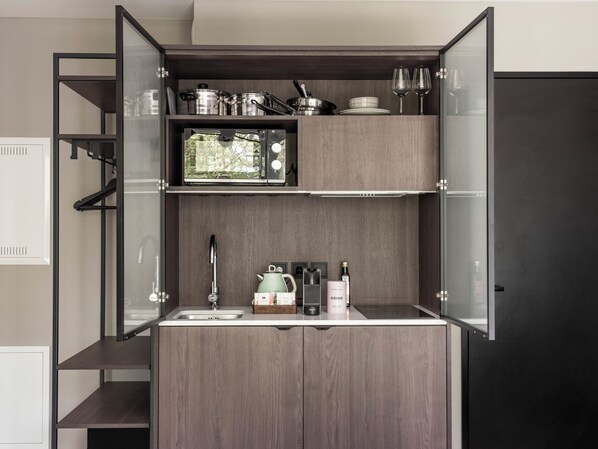 A compact kitchen with a built-in microwave, a sink, and a coffee maker. - Numa | Munich Obersendling (Munich)
