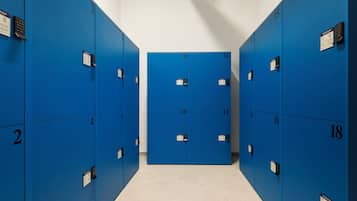 A row of blue lockers numbered from 2 to 18 in a hallway with a tiled floor.