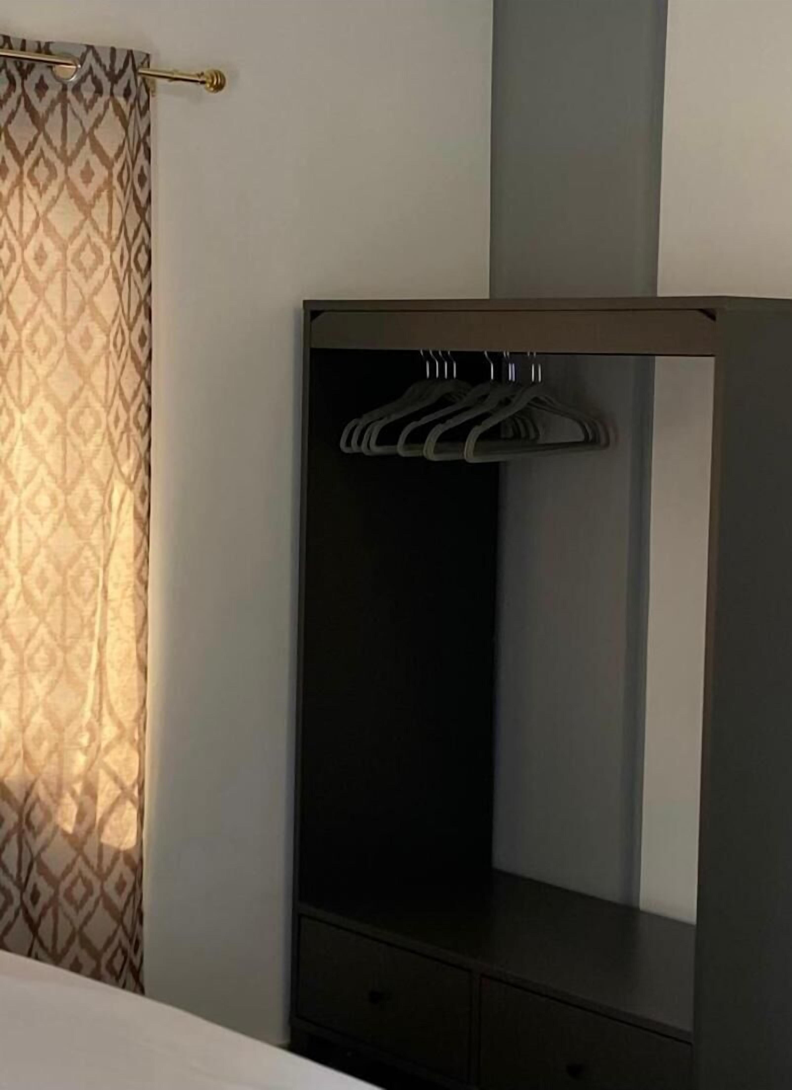 A wardrobe with multiple hangers and a mirror.