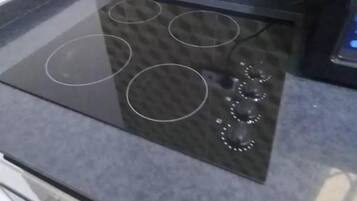 A kitchen with a black induction cooktop, a tiled backsplash, and a power outlet.