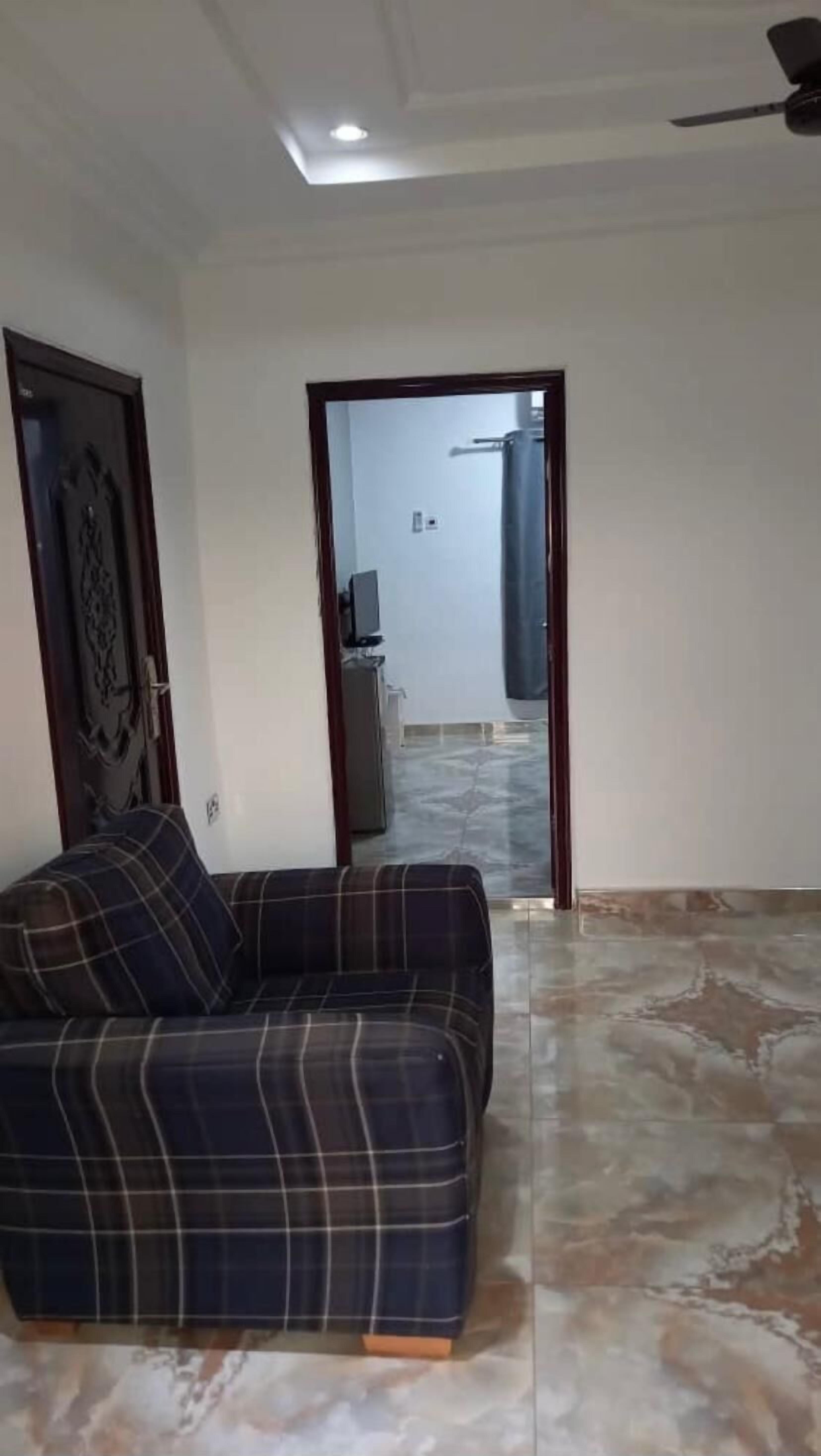 A living room with a sofa, a ceiling fan, and a view into another room through an open doorway.