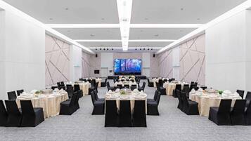 A conference room with round tables, black chairs, and a large screen at the front.
