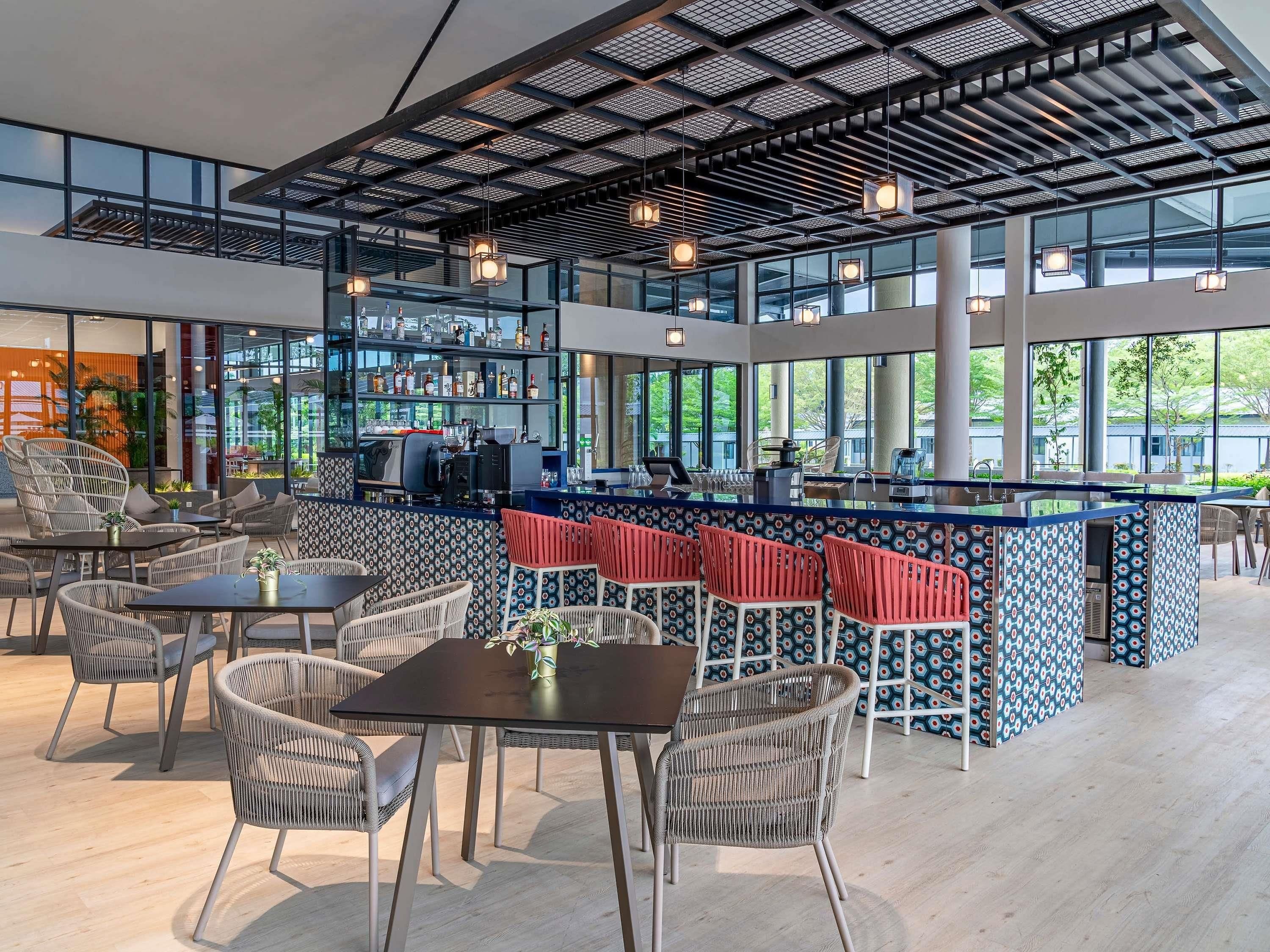 A modern bar area with seating, a counter, and large windows.