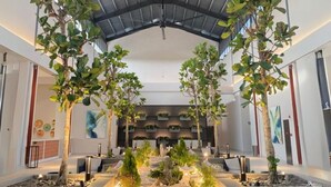 A modern indoor space with a high ceiling, large windows, and a central seating area with planters. - Ibis Styles Sepang Klia (Sepang)