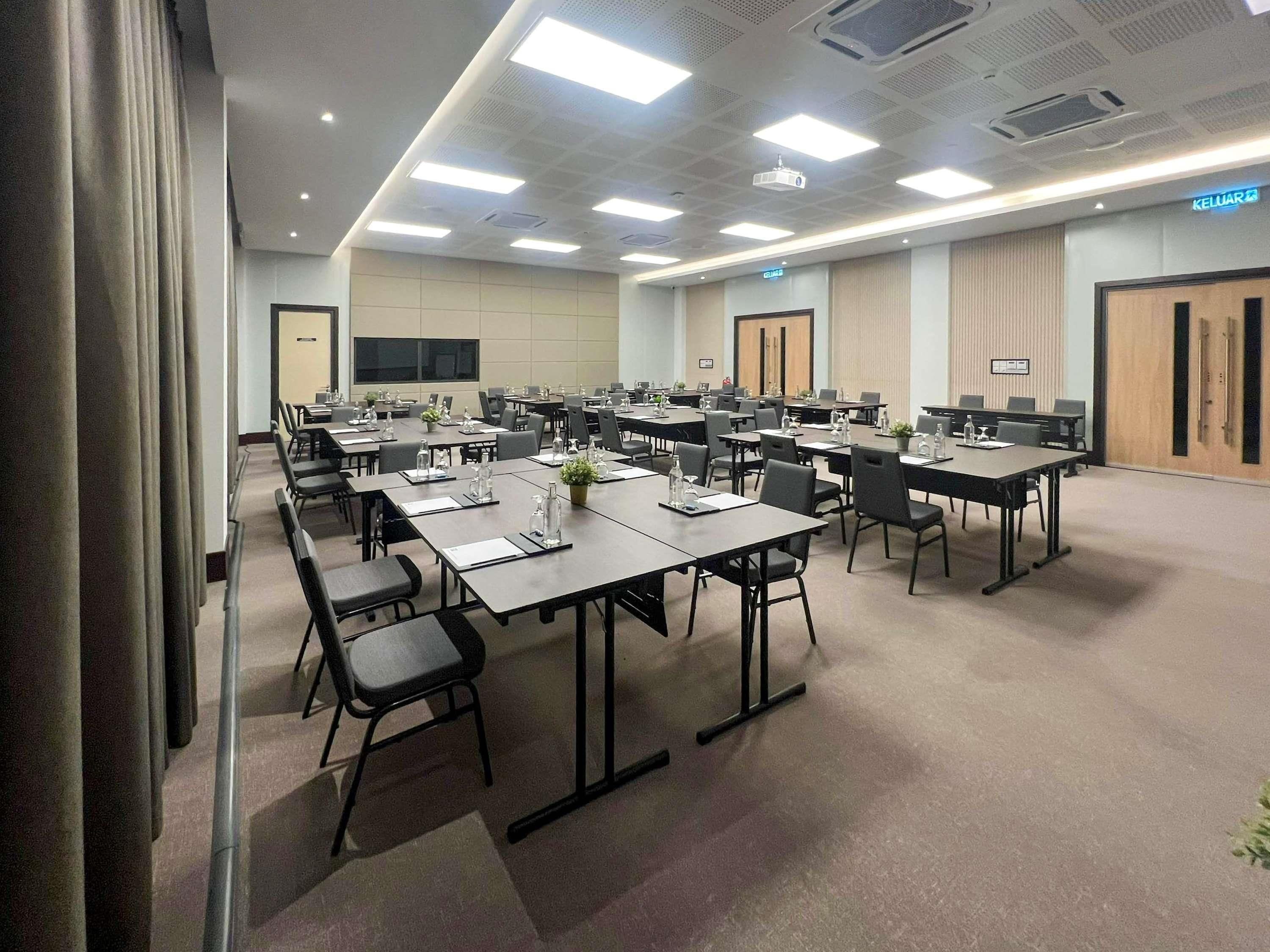 A conference room with multiple tables and chairs, equipped with water bottles and nameplates.