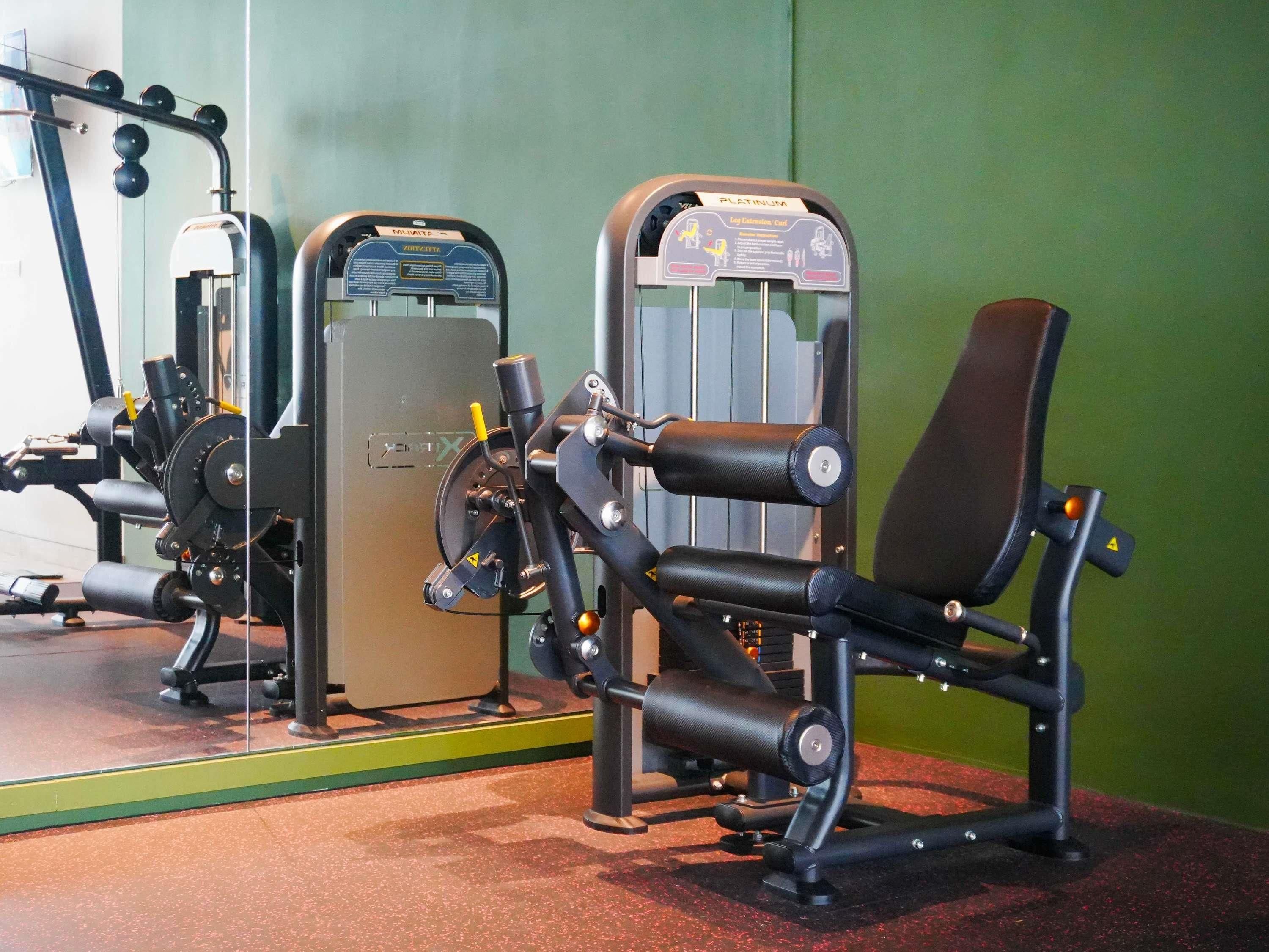 Ein Fitnessraum mit Trainingsgeräten, darunter eine Beinpresse und eine Brustpresse.