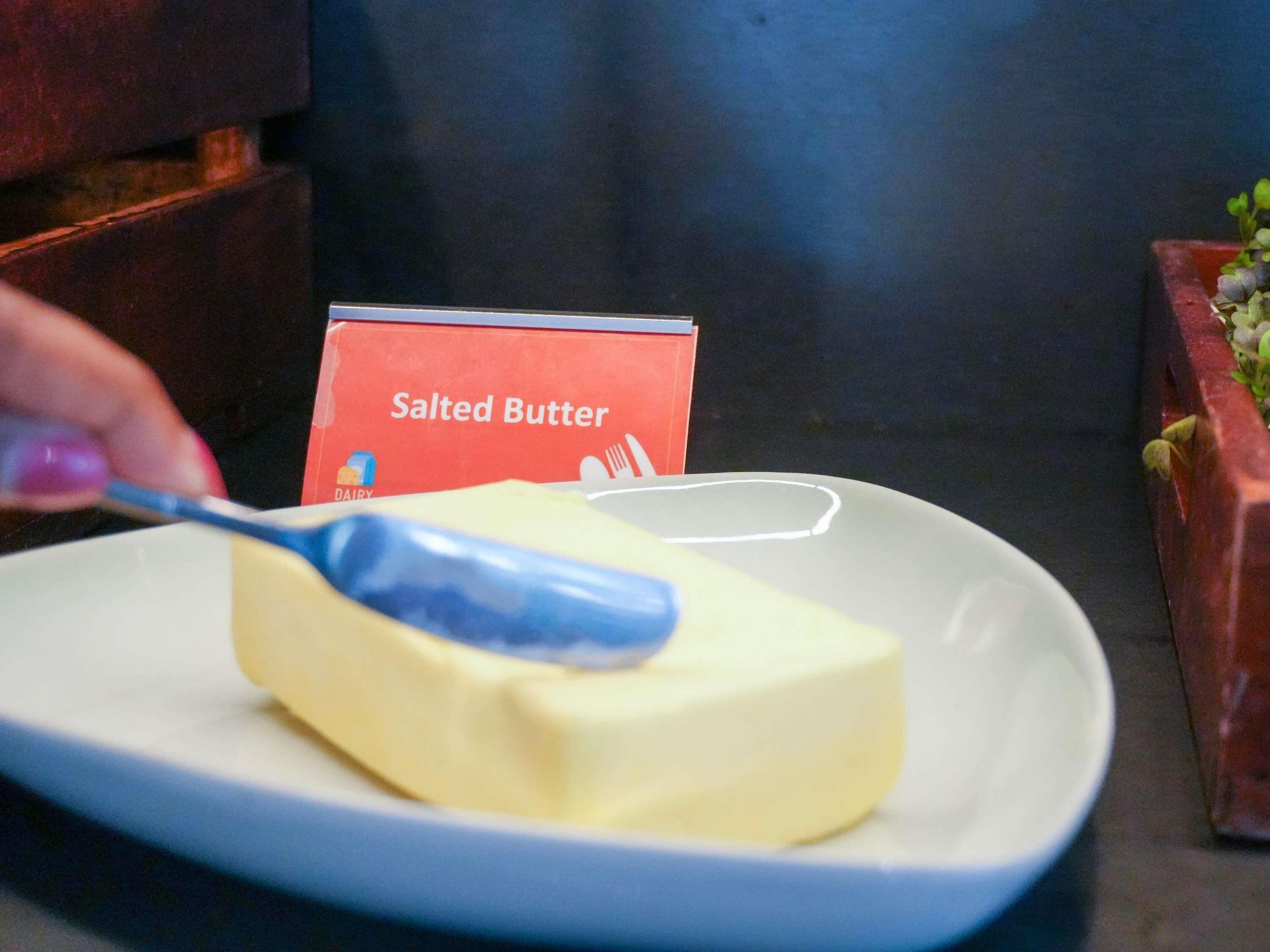A plate with a block of butter and a butter knife on a white plate.