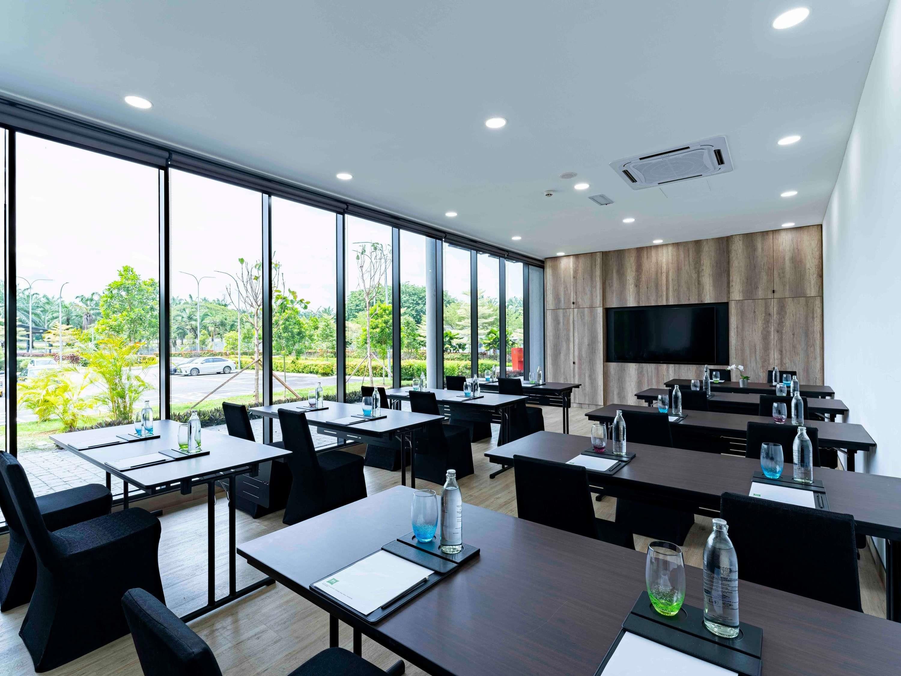 A modern conference room with large windows, a flat-screen TV, and a wooden panel wall.