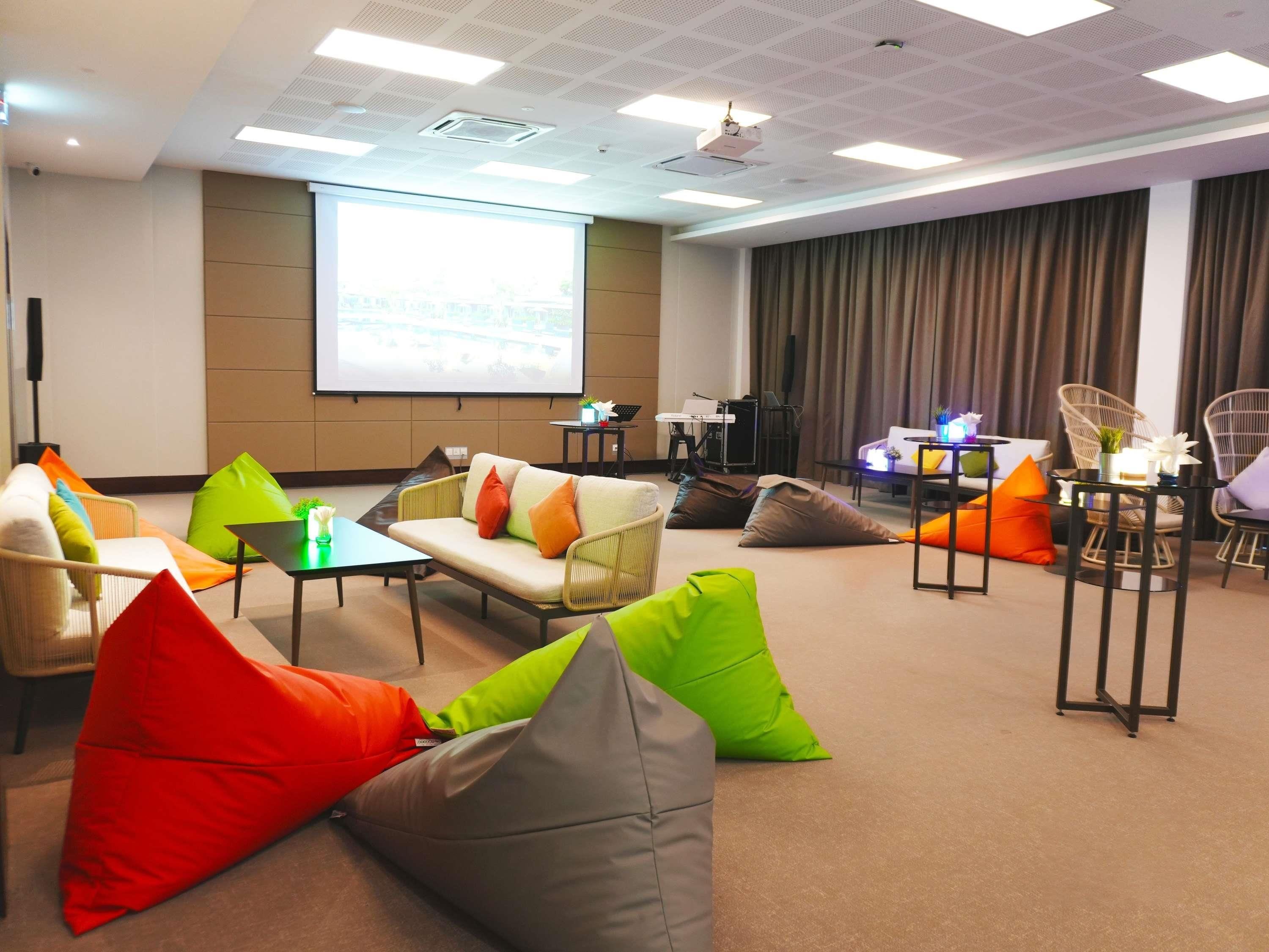 A conference room with a projector screen, seating arrangements, and a presentation area.