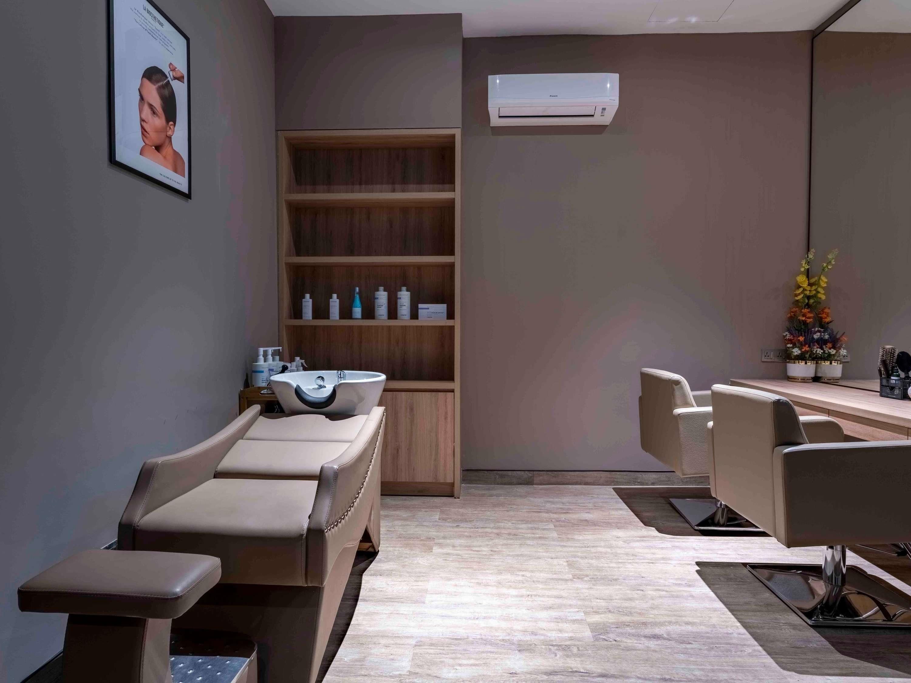 A spa room with a massage chair, a shelf with toiletries, and a wall-mounted air conditioner.
