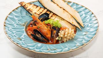 A seafood dish with grilled bread on a ceramic plate.