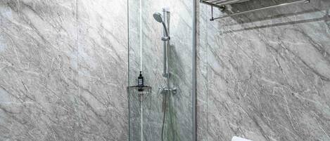 A modern shower with a glass enclosure, a chrome showerhead, and a towel rack.