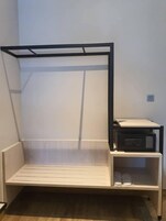 A bunk bed with a desk and a microwave on the side.