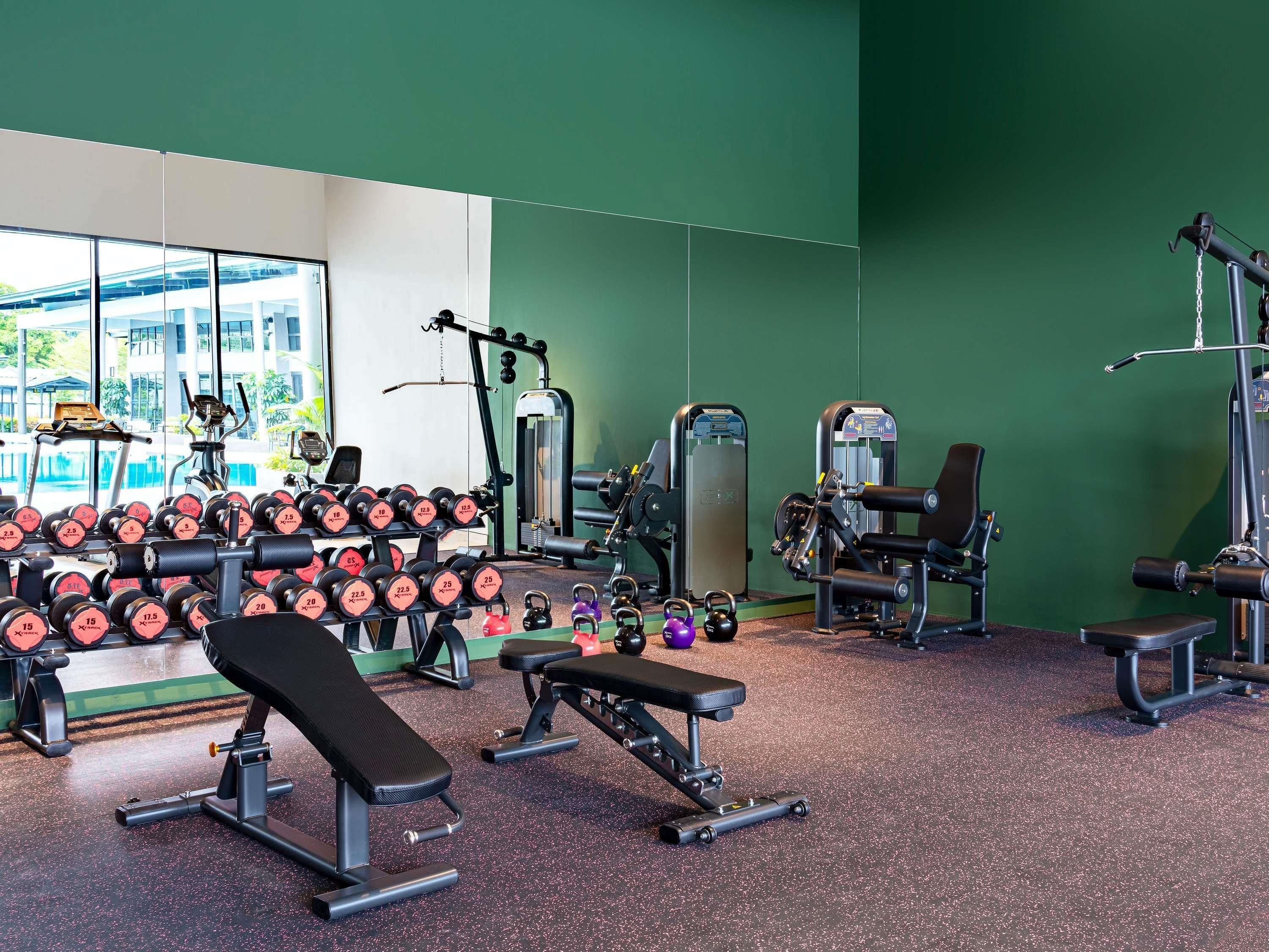A gym with exercise equipment, benches, and dumbbells.