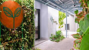A covered outdoor area with a wall of greenery, a large orange sign with a leaf design, and a sign that reads 'LET NATURE HEAL.'