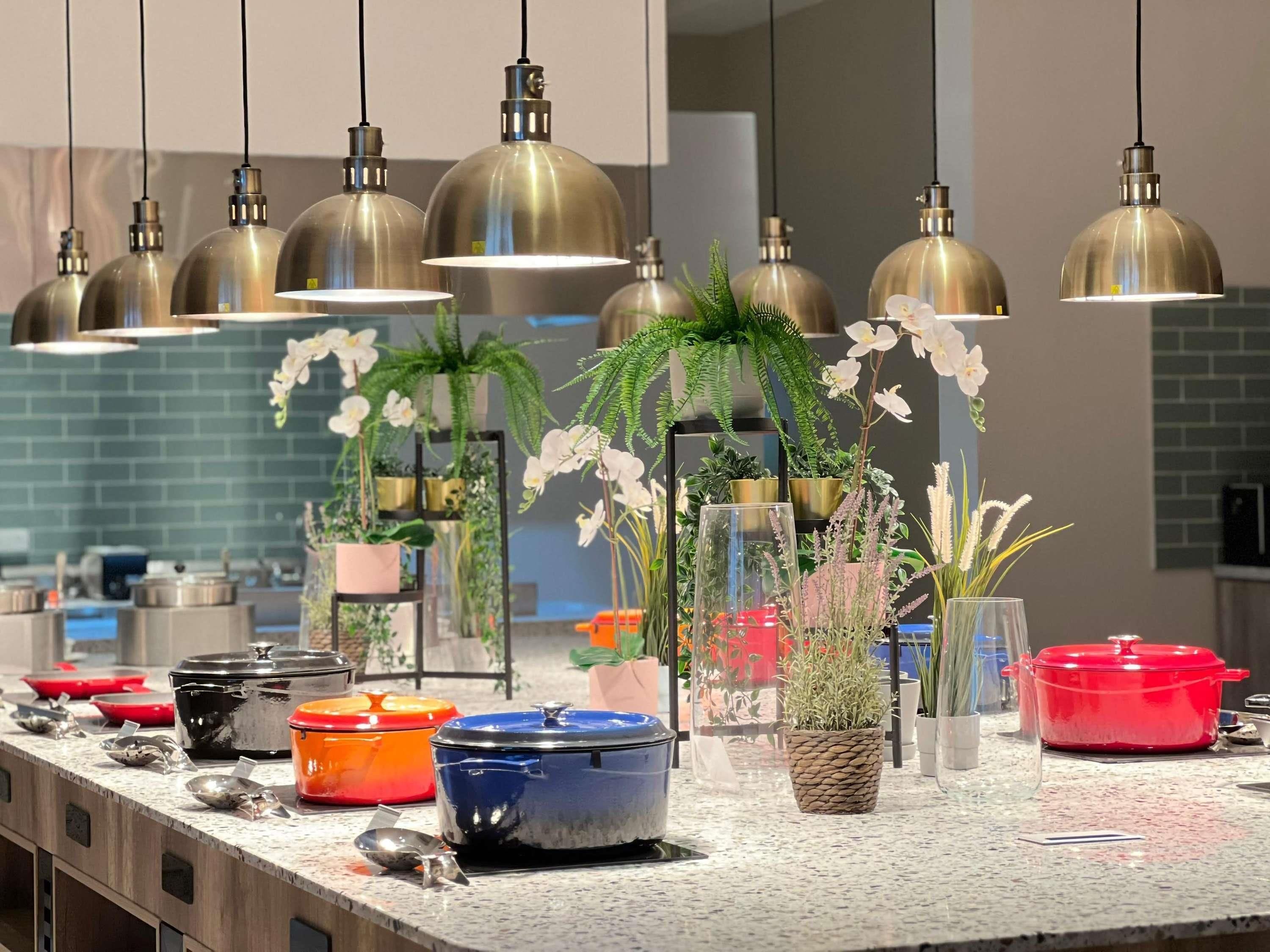 Una cocina con lámparas colgantes, plantas en macetas y diverso menaje.