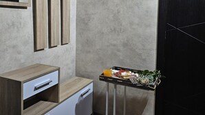 Een hoek van een kamer met een houten kast, een klein tafeltje met eten en drinken, en een donkere deur.
