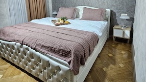 Een slaapkamer met een bed, een nachtkastje, een lamp en een raam met gordijnen.