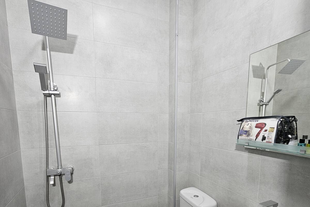 Uma casa de banho moderna com chuveiro, sanita e lavatório.