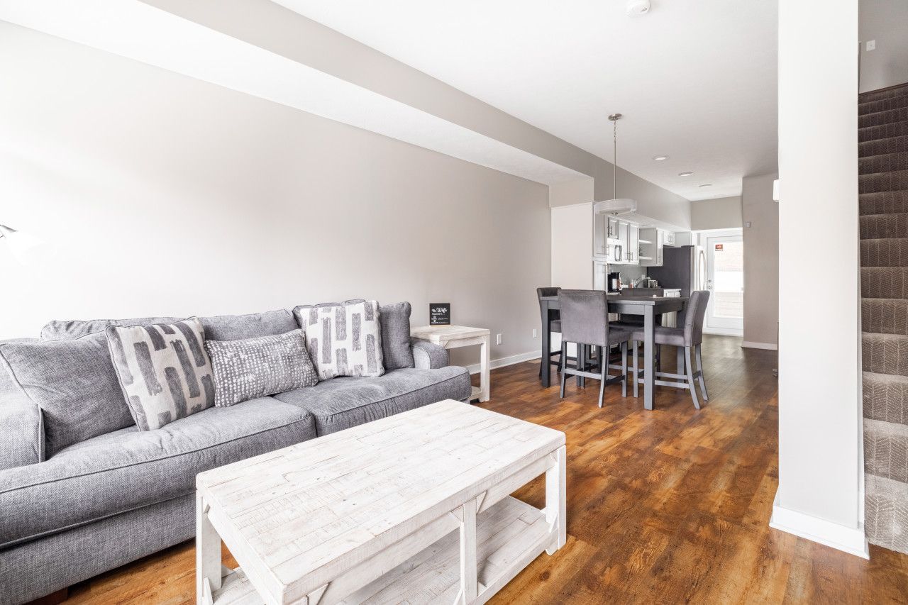 A modern living room with a gray sofa, white coffee table, and hardwood flooring.