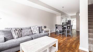 A modern living room with a gray sofa, white coffee table, and hardwood flooring.