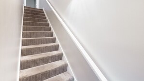A staircase with carpeted steps leading to a door. - Luxury Downtown Townhome w/ Private Garage Unit 5 (Cleveland)