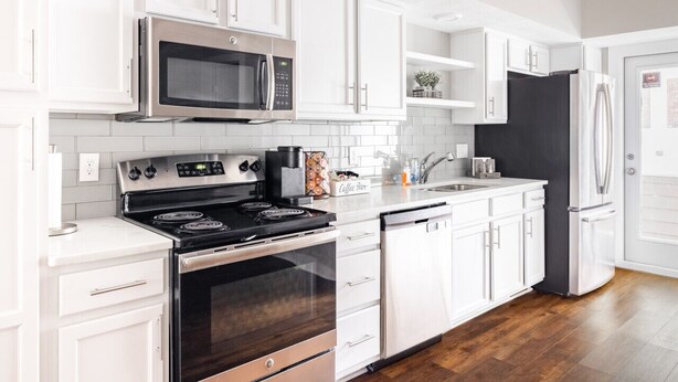 A modern kitchen with white cabinetry, stainless steel appliances, and a black refrigerator. - Luxury Downtown Townhome w/ Private Garage Unit 5 (Cleveland)