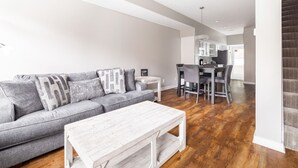 A modern living room with a gray sofa, white coffee table, and hardwood flooring. - Luxury Downtown Townhome w/ Private Garage Unit 5 (Cleveland)