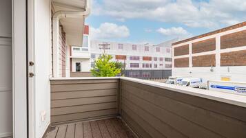 A corner balcony with a view of a parking area and a building with multiple garage doors.