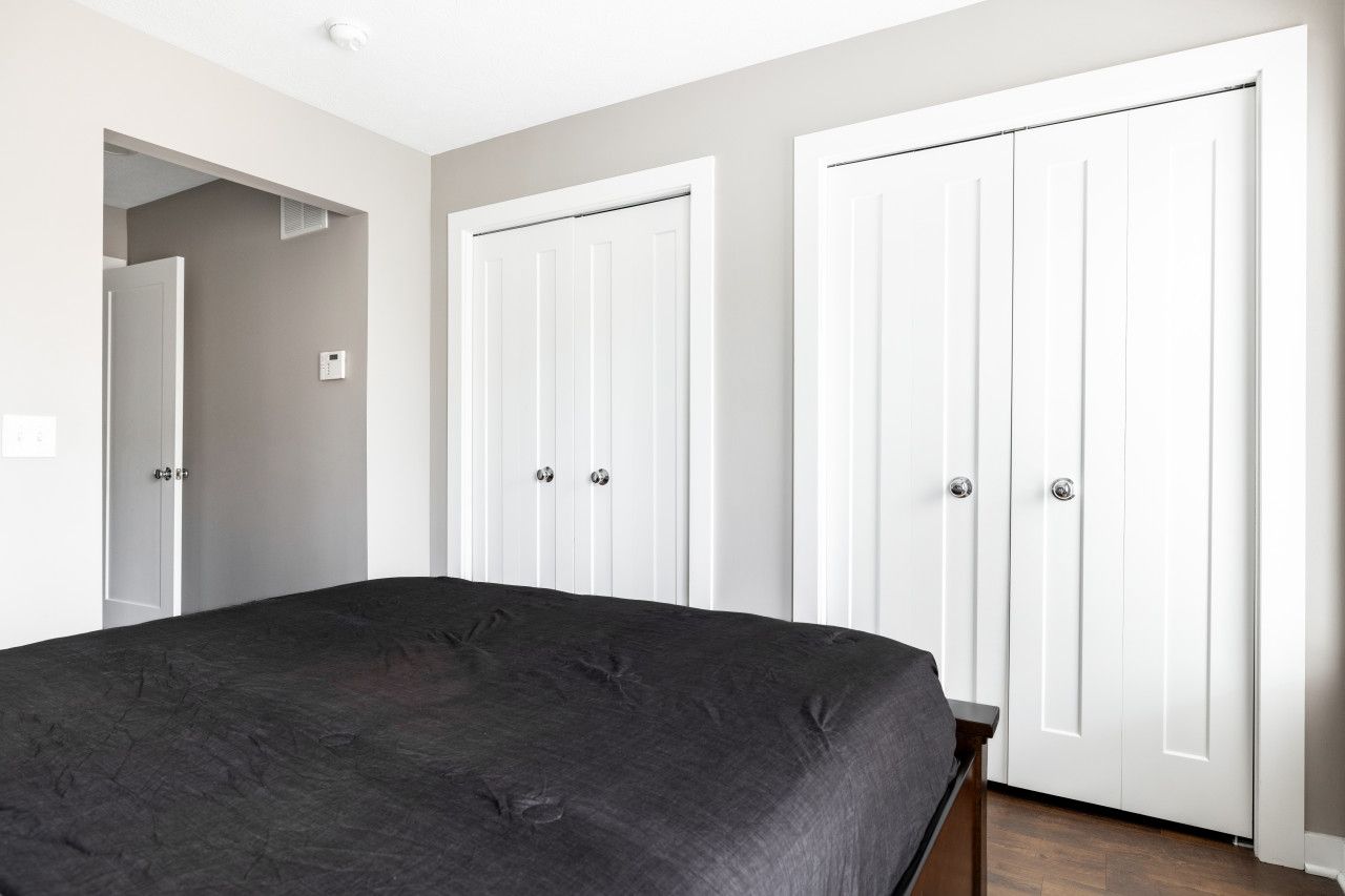 A bedroom with a large bed, two white wardrobes, and a door leading to another room.