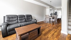 En stue med en lædersofa, et træsofa bord og et spiseområde med stole og et bord.