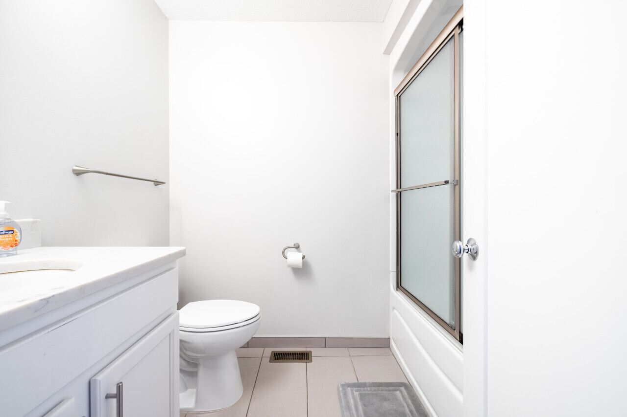A small, modern bathroom with a toilet, a sink, and a shower area.