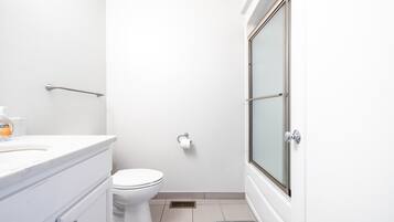 A small, modern bathroom with a toilet, a sink, and a shower area.