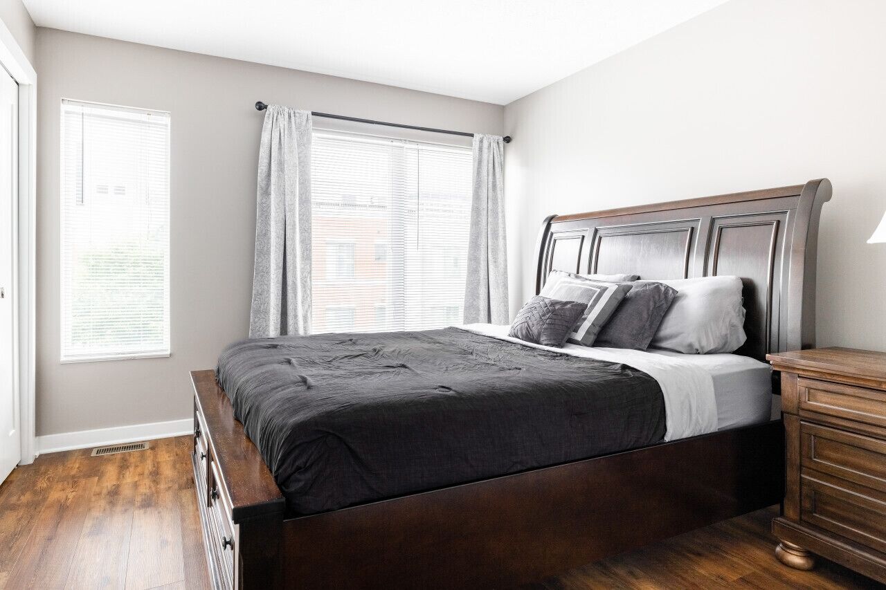 A bedroom with a wooden bed, a nightstand, and a window with curtains.