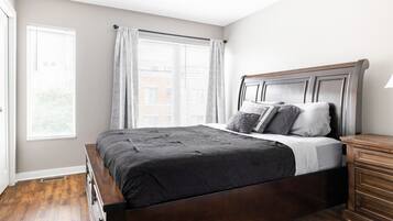 A bedroom with a wooden bed, a nightstand, and a window with curtains.