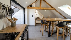 A kitchen with wooden beams, a dining area with wooden chairs, and a view of the adjacent room. - Lac et montagne, charmant appartement idéalement placé! (Sévrier)