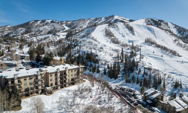 A ski resort with multiple buildings, a ski lift, and a snow-covered mountain backdrop.
