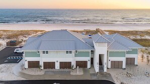 A coastal building with multiple garages, a parking lot, and a view of the ocean. - Maritime Manor | Incredible On-Site Amenities + Beach Club! (Perdido Key)