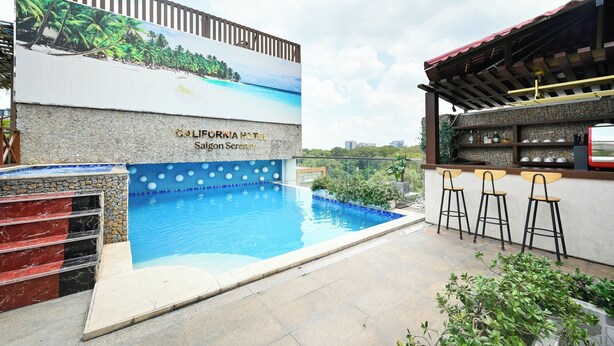 Un área de piscina con un letrero del California Hotel Sagong Serenity, un bar con taburetes y una pared de piedra.