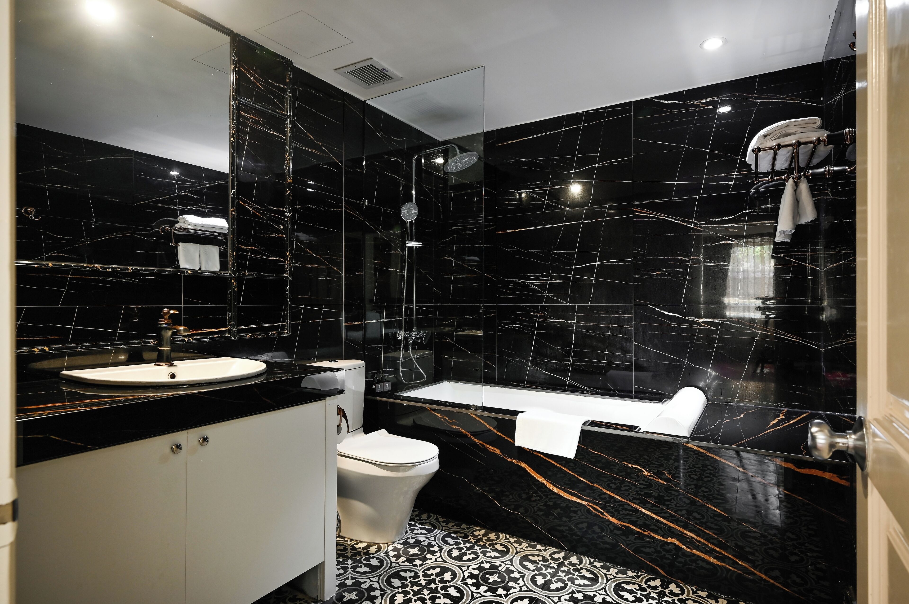 A modern bathroom with a black marble sink, toilet, and bathtub.