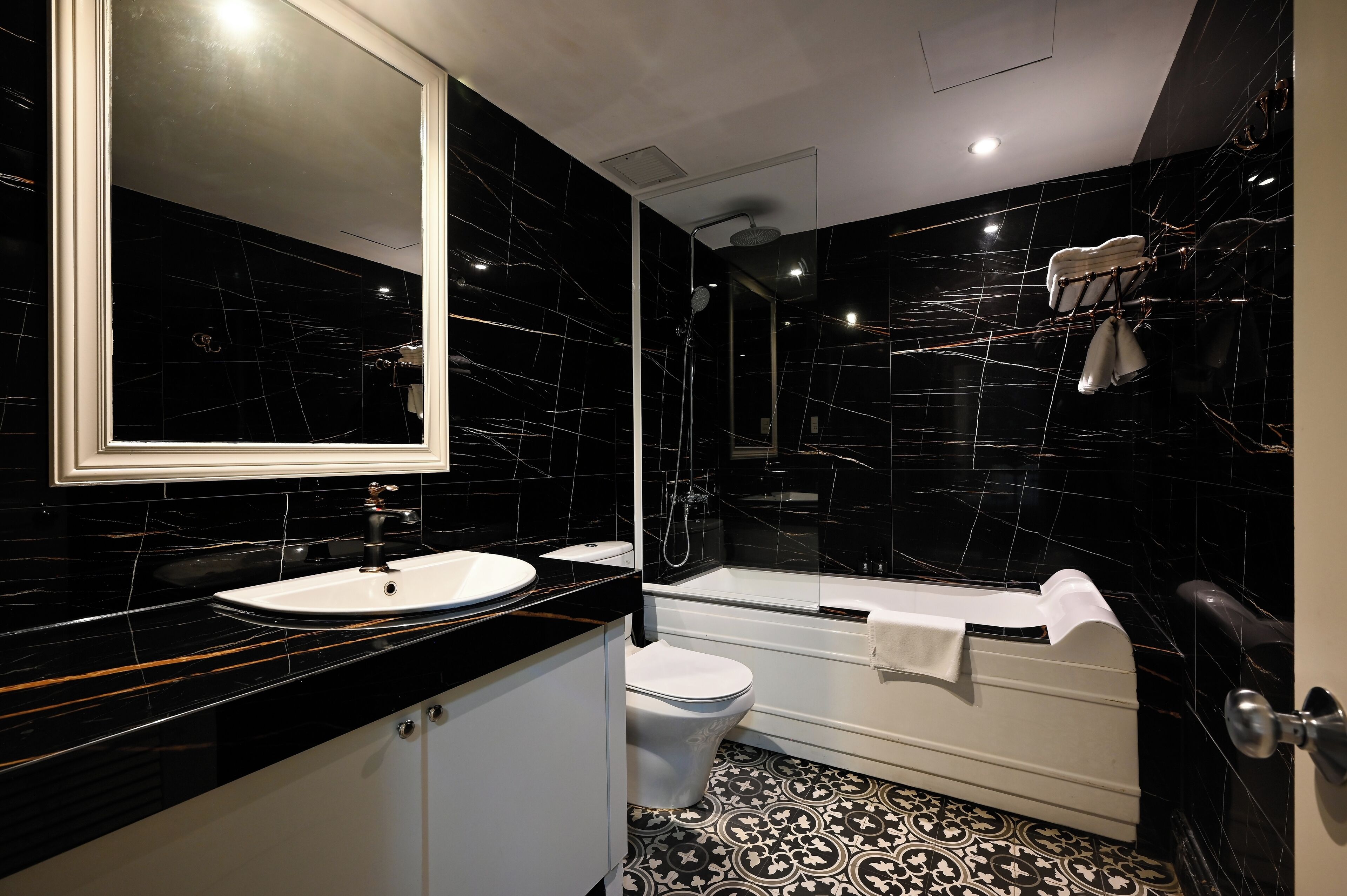 Un baño moderno con lavamanos de mármol negro, inodoro blanco y cabina de ducha con paredes de vidrio.